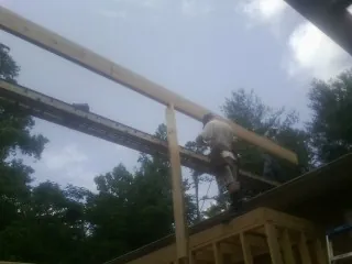 Carpenter setting a ridge beam over a new addition frame — Ice Dam Removal by Roofing Brothers in Beach